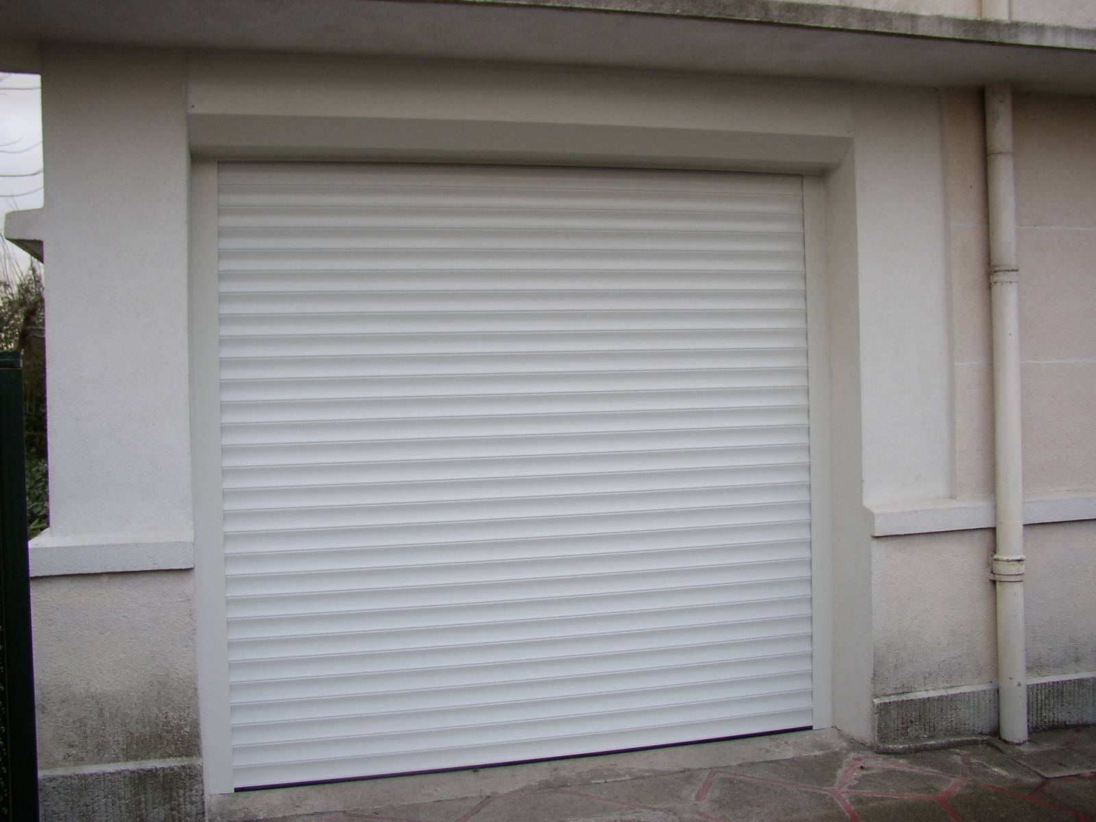 La porte de garage à lames enroulables préserve l’espace dans le garage : adaptable, performante, manuelle ou motorisée, elle peut se placer sur une rue passante en offrant toute la sécurité nécessaires.