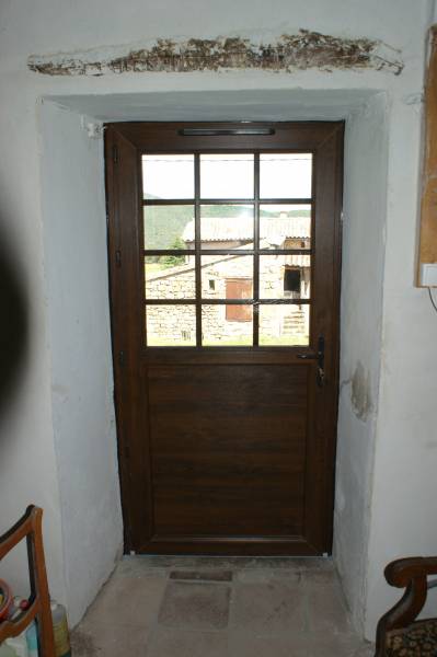 Vue intérieure d'une porte type fermière en PVC acajou petit bois intégré au vitrage, serrure et seuil PMR sur Notre Dame de Londres